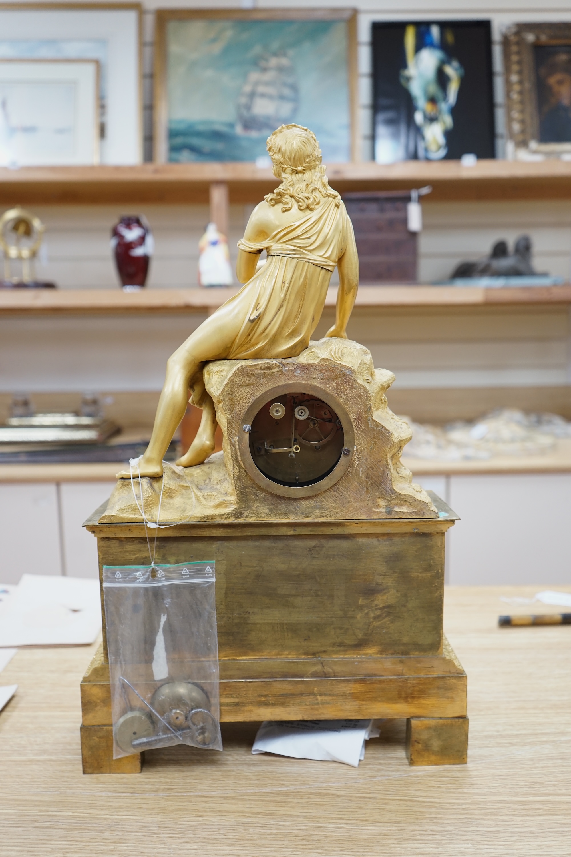 A French Louis Philippe period Empire ormolu clock, with seated classical female upon a rock enclosing the dial, the whole upon a square base with allegorical patch in relief, c.1830, with key, 57cm high. Condition - fai